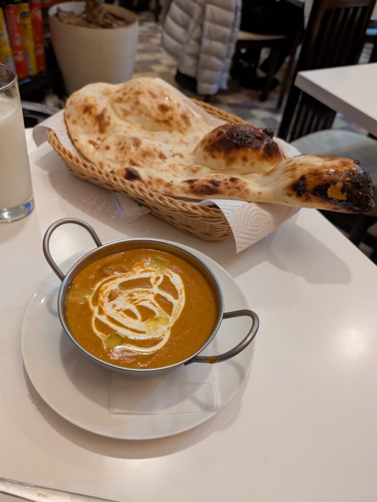 a bowl of butter chicken and a naan